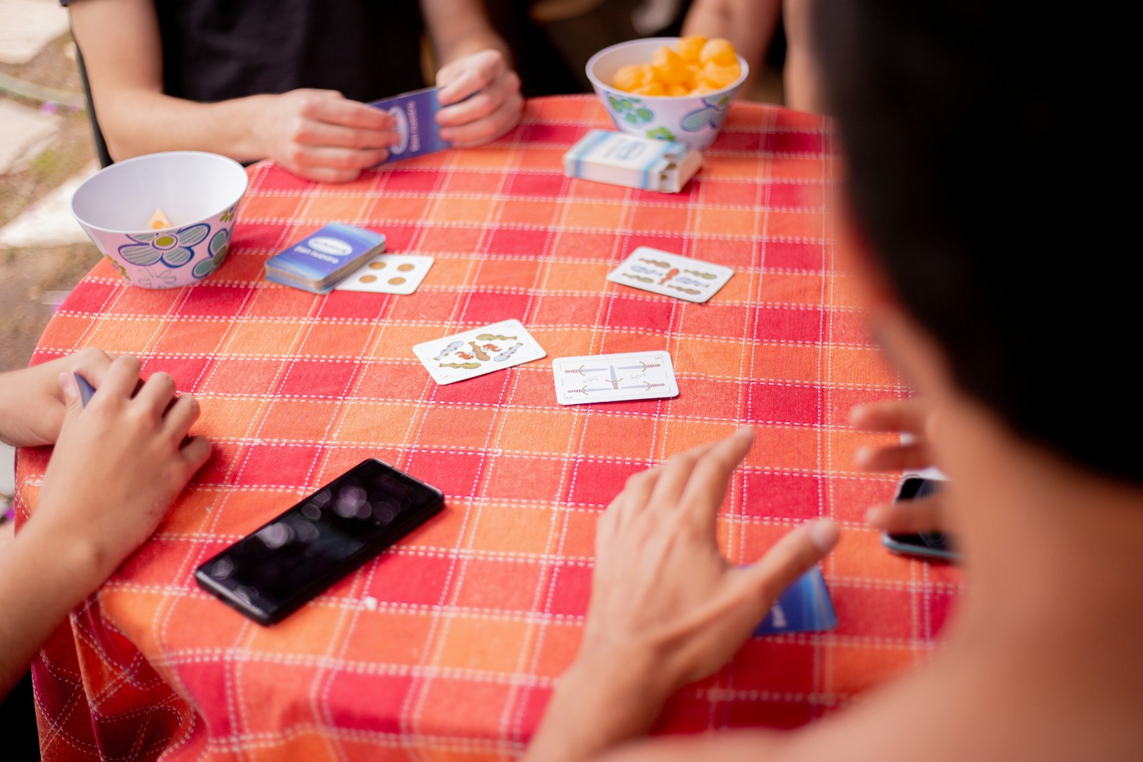 A multi-generational family enjoying the hand and foot card game around a table.