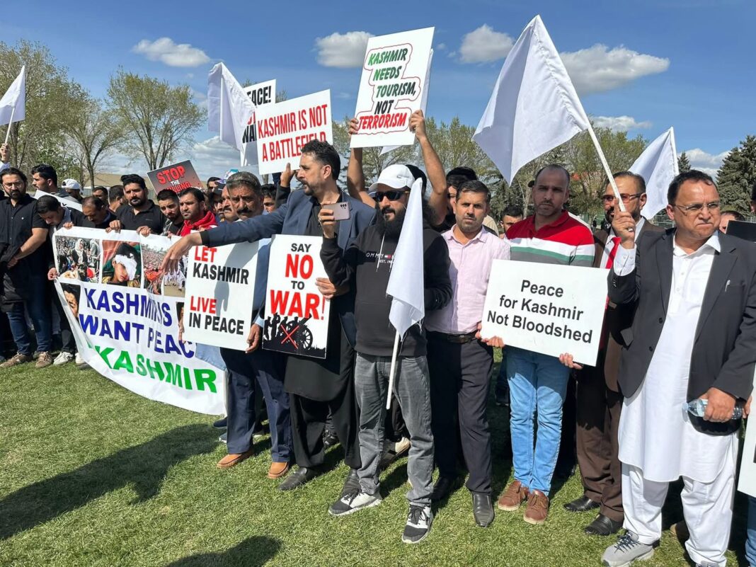 A group of Kashmiri protesters in Calgary holding white flags and placards reading 