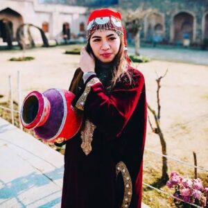 A young Kashmiri girl stands wearing traditional Kashmiri dress.