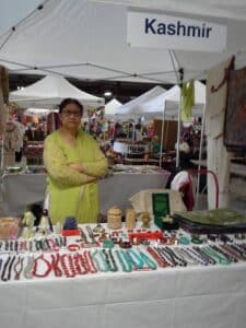 Kashmiri handicrafts stall at an international exhibition, displaying pashmina shawls, carpets, and papier-mâché art alongside exhibits from Russia, India, and Pakistan. The booth attracts thousands of visitors and global media attention, symbolizing Kashmir’s distinct cultural identity and the diaspora’s role in advocating for recognition and self-determination.