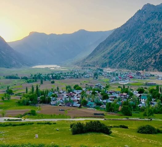 A breathtaking view of Gurez Valley in northern Kashmir, located about 8,000 feet above sea level in the Himalayan mountains. The turquoise lake reflects the rugged rocky peaks under a clear blue sky, capturing the untouched natural beauty and serene landscape of this remote high-altitude valley. In this region of Azad Kashmir, the Shina language is spoken, and the lifestyle closely resembles that of Gilgit-Baltistan, reflecting a unique blend of cultural and geographical harmony.